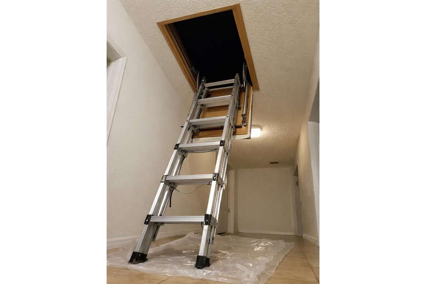 A folding ladder lowered from an open attic hatch